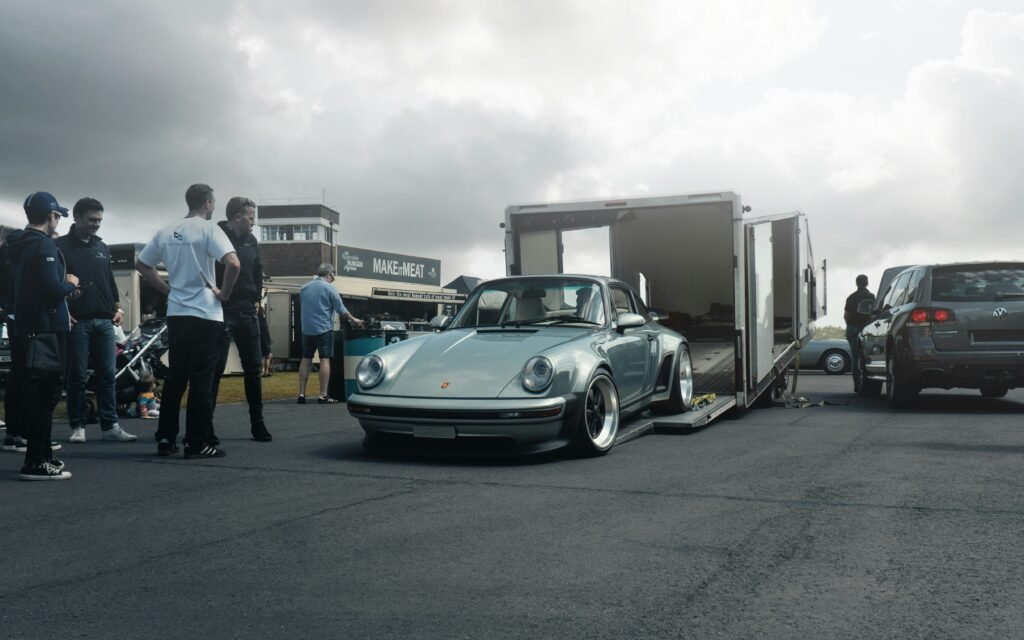 Porsche classique argent sortie d'une remorque fermée, service de transport sécurisé de véhicules de prestige en Europe