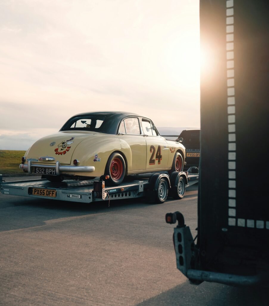 Voiture de collection jaune numéro 24 transportée sur remorque au coucher de soleil pour livraison de luxe