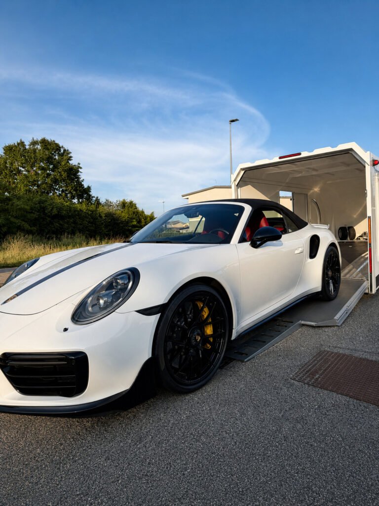 Porsche 911 Turbo S cabriolet blanc en cours de chargement dans une remorque fermée pour transport sécurisé