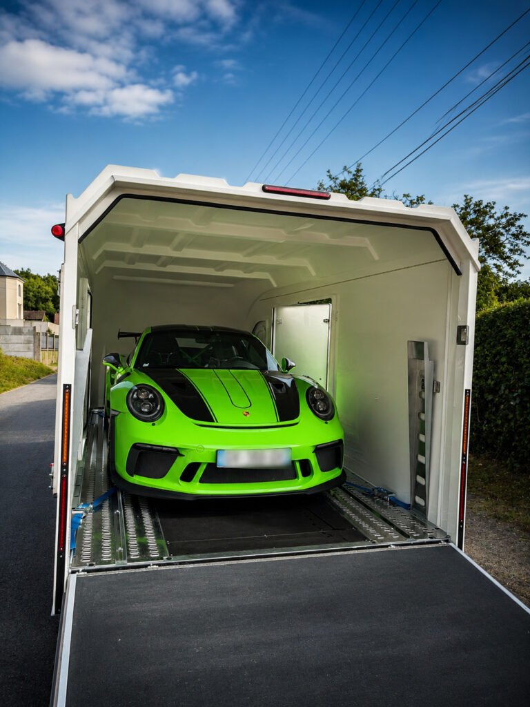 Porsche 991.2 GT3 RS verte chargée en remorque fermée, sangles par roue et double rampe pour transport sécurisé Paris‑Cannes