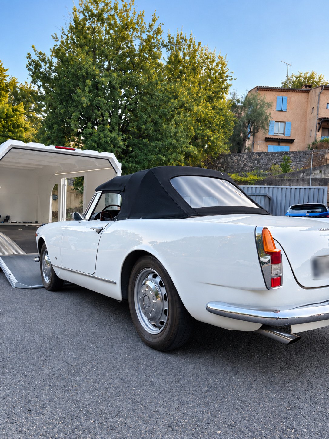 voiture de collection blanche en train d'être chargée dans la remorque de transport fermée